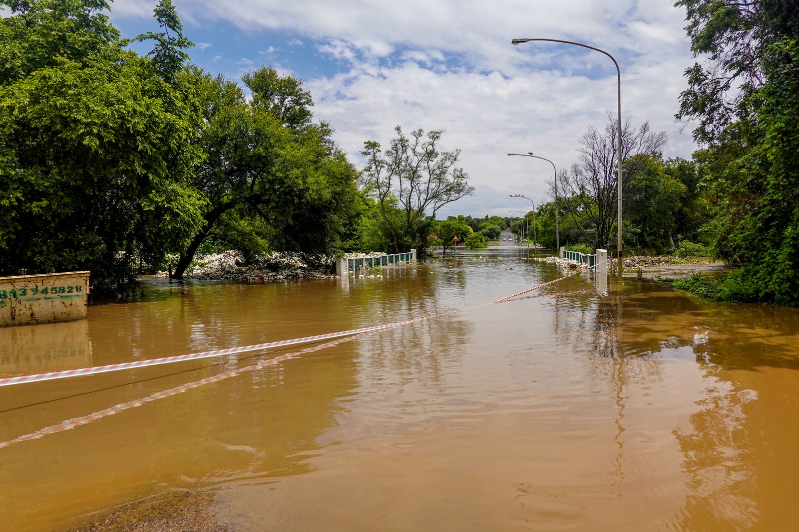 A rural road closed off and covered by muddy floodwater after heavy rain