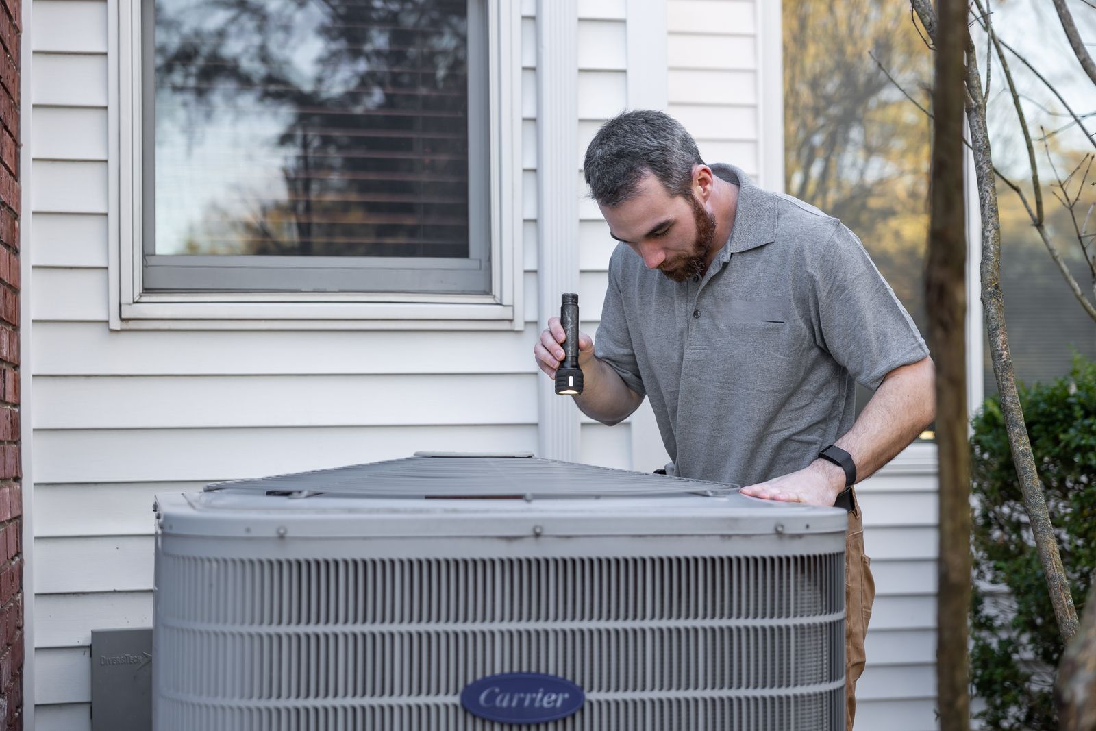A technician inspecting an outdoor HVAC unit