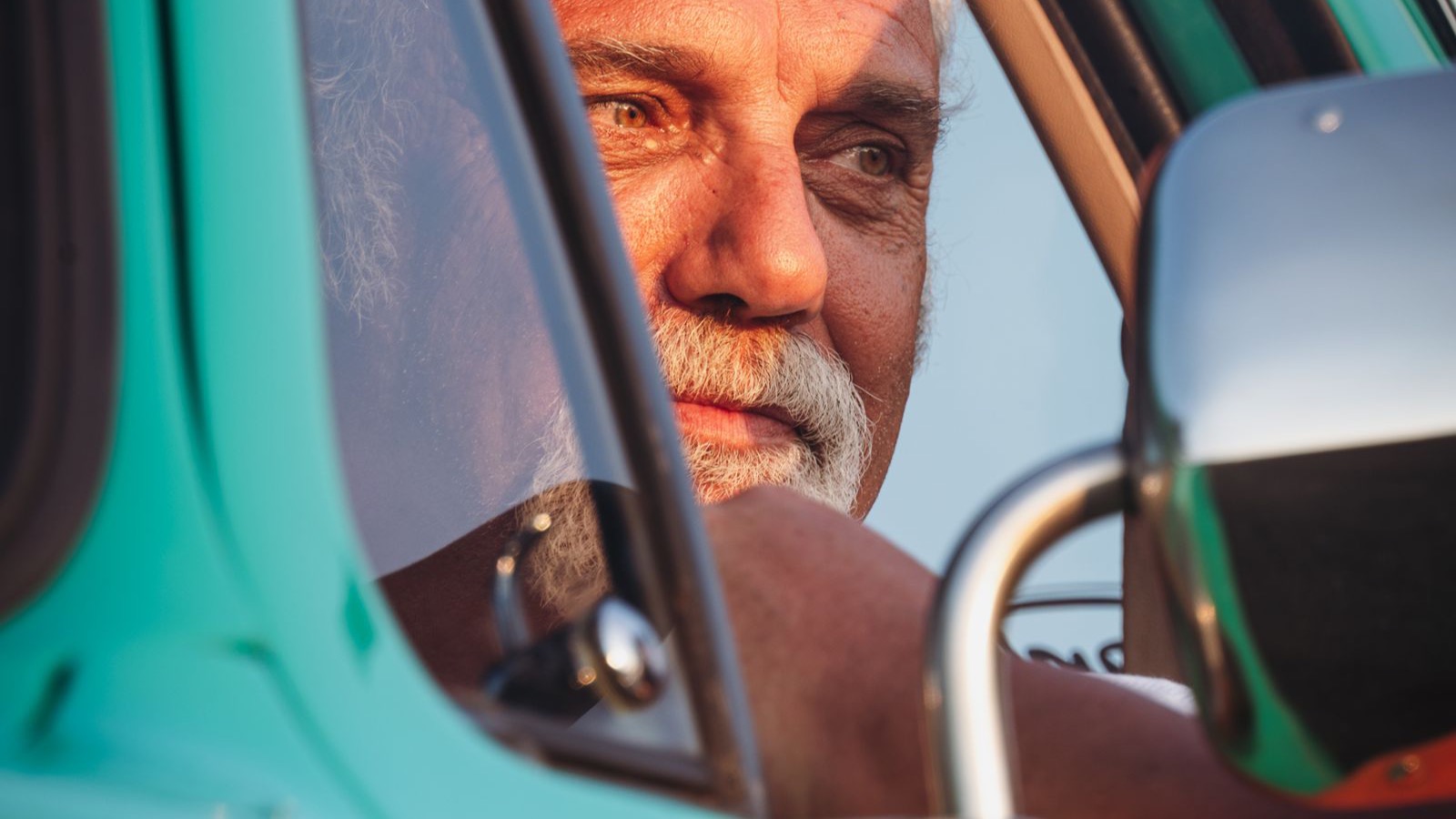 An older man driving a classic car