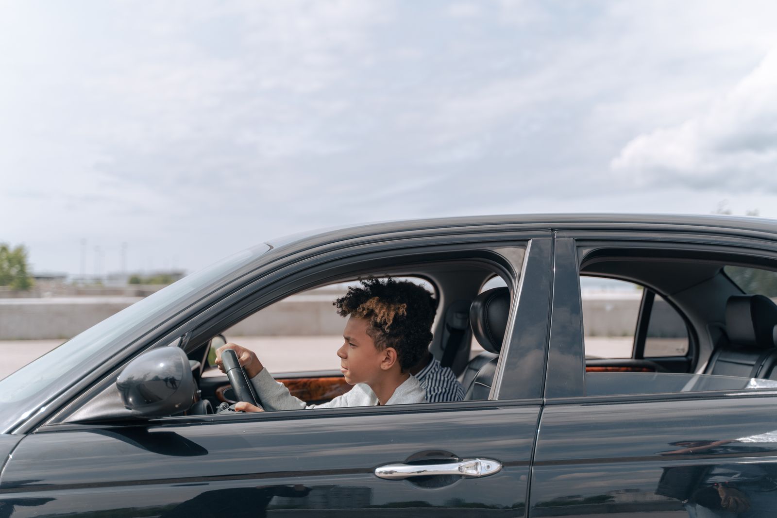 A young driver in a brown jacket behind the wheel