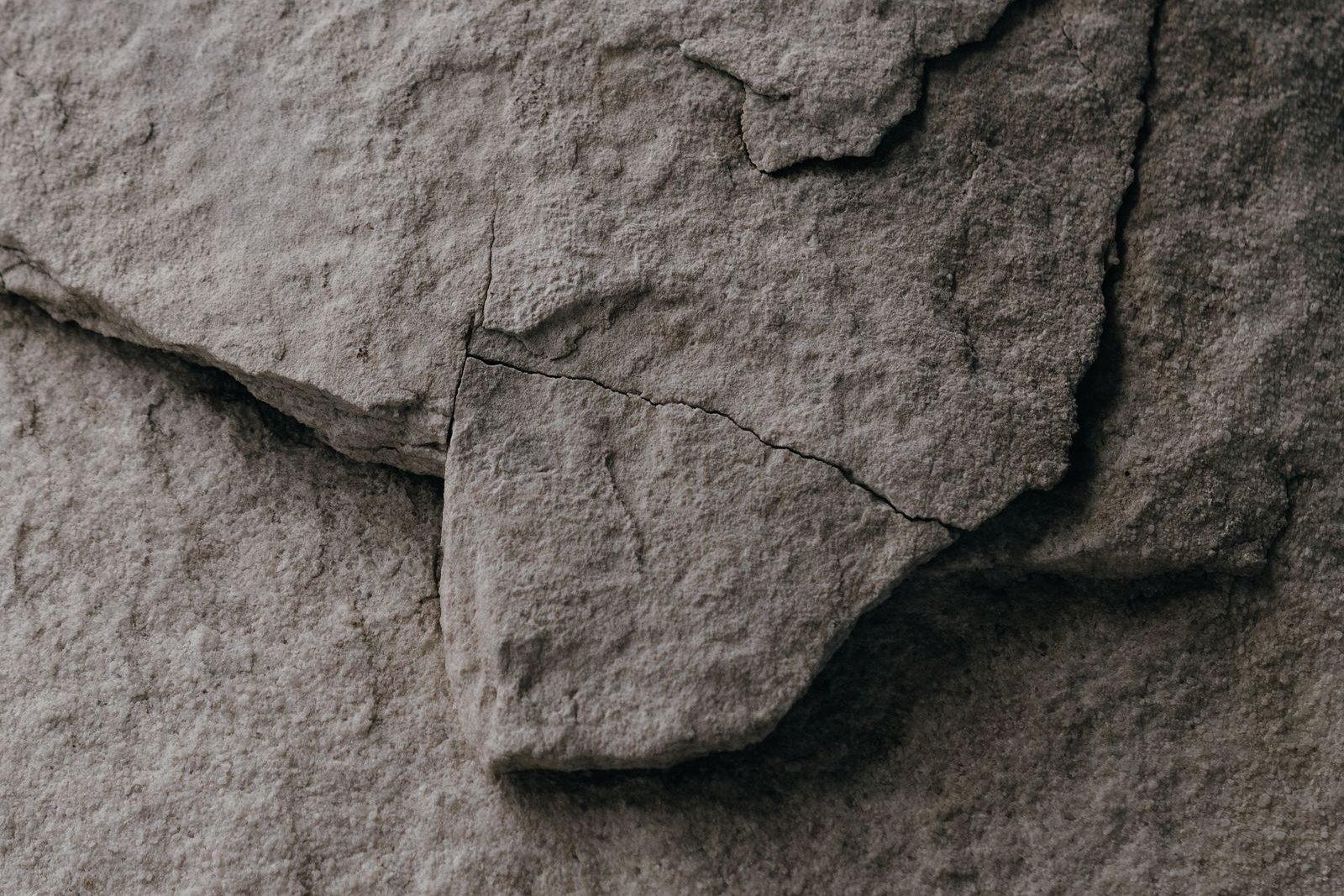 Close-up of a weathered gray stone surface broken by fractures, with one slab pushed slightly out of line